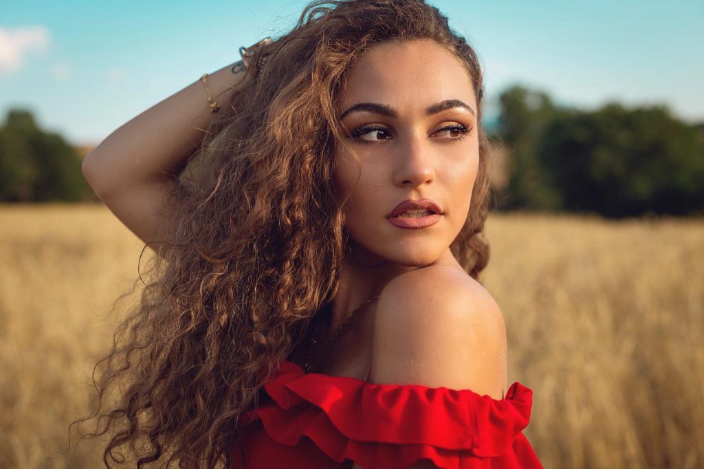 Carlotta in abito rosso in un campo di grano a Pienza Val d'Orcia
