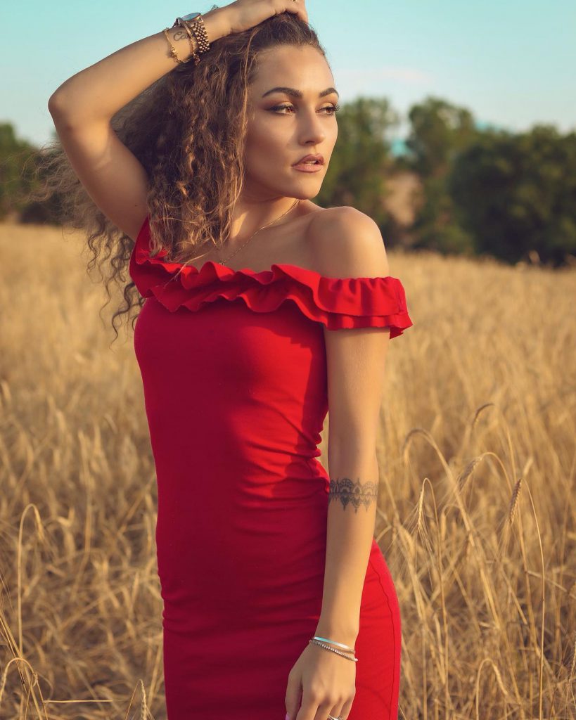 Carlotta in abito rosso in un campo di grano a Pienza Val d'Orcia